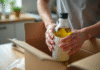 Main emballant une bouteille d'huile d'olive dans du papier bulle