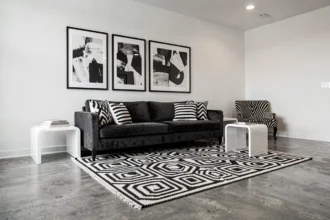 Salon graphique noir et blanc avec tapis géométrique, canapé en velours charbon et œuvres d'art abstraites en noir et blanc